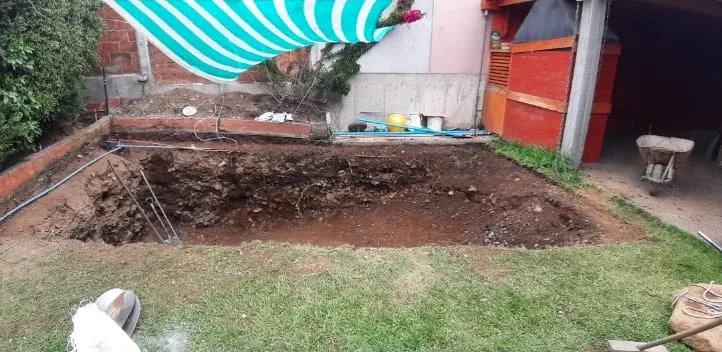 Excavación abierta en el patio de una casa, con la tierra extraída