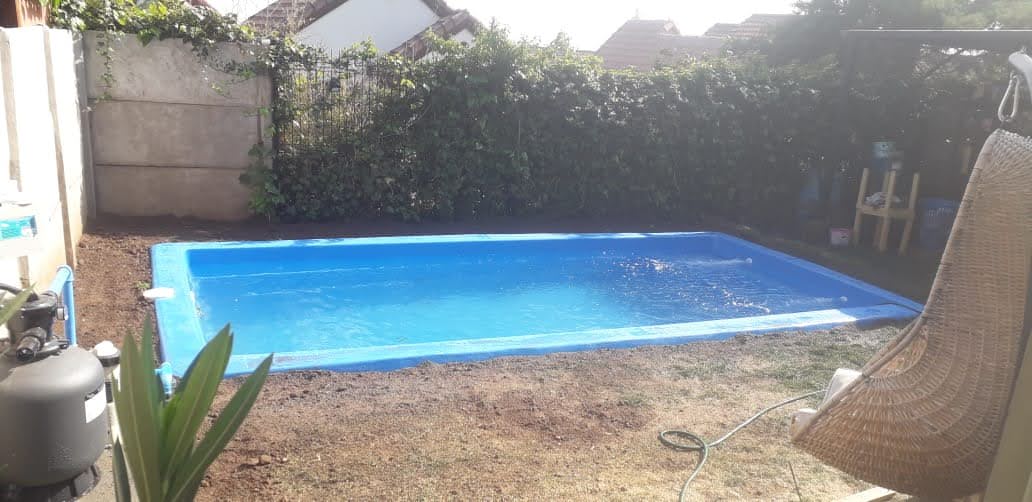 Piscina de fibra de vidrio de 7 por 3 metros, terminada y llena de agua en el patio de una casa
