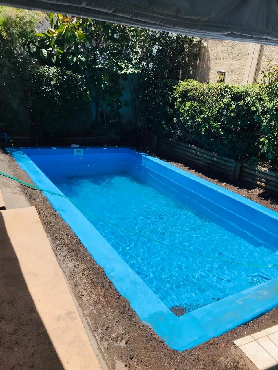 Piscina instalada y llena, con el patio todavía en tierra